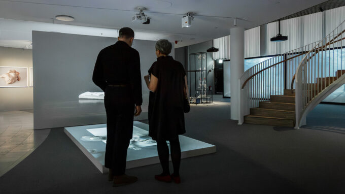 En man och en kvinna tittar på ett av verken på en digital skärm från utställningen Borderlands.