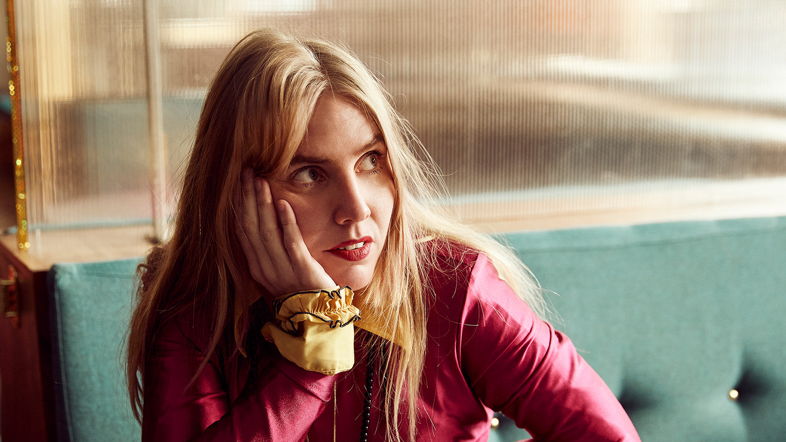 Blond kvinna klädd i rött som tittar bort från kameran.